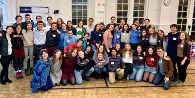 A group of more than 20 young Bronfman alumni stand in a room and pose for the camera.