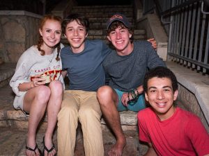 Fellows sitting together on some steps and smiling.