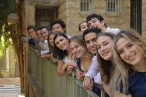 Fellows standing in a row over a balcony and smiling