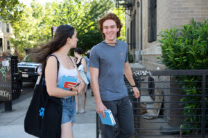 A young man and woman walk together, smiling.