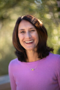Picture of Hilary Caplan Somorjai, with brown hair and a purple shirt.