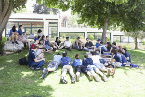 Fellows learning in a circle on the grass.